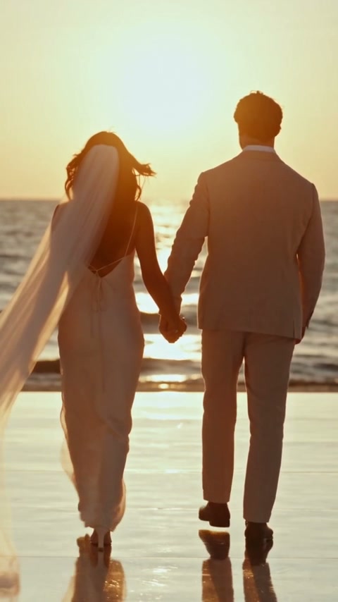 The couple walking beside the pool toward the setting sun